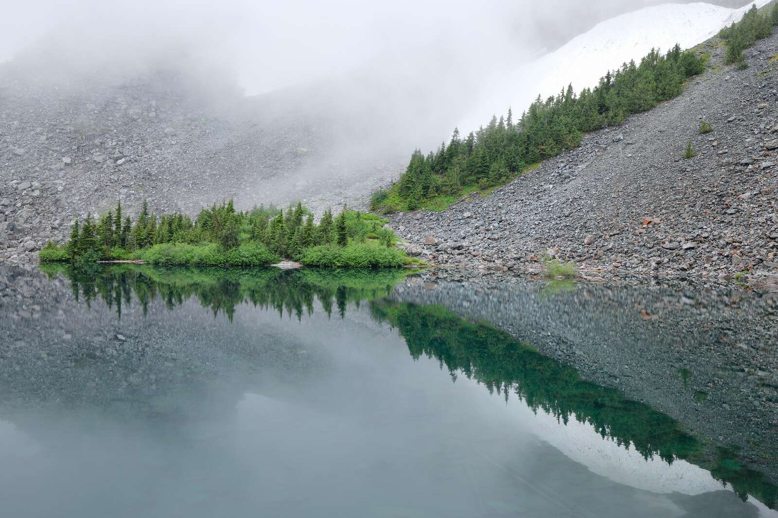 Bright trees and snow reflecting over a lake